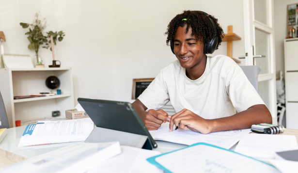 Student engaged in online cybersecurity learning with headphones and laptop in modern study environment